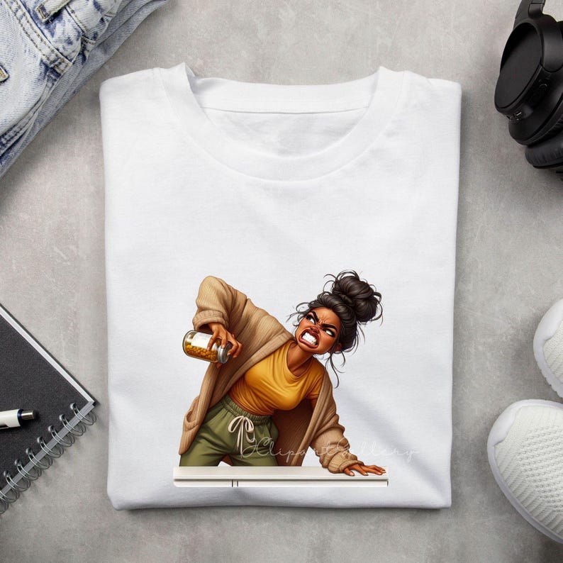 Puede incluir: Camiseta blanca con una ilustraci&oacute;n de dibujos animados de una mujer sosteniendo un tarro. La mujer lleva una camiseta amarilla, pantalones verde oliva y una rebeca color canela. Su expresi&oacute;n es de frustraci&oacute;n. La camiseta es de cuello redondo.