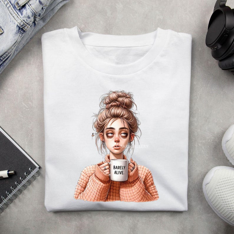 May include: White t-shirt with a graphic of a woman with messy hair holding a coffee mug that says "Barely Alive".
