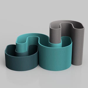 May include: Abstract, modern sculpture in teal and gray. The design features three cylindrical forms with vertical ridged textures. The teal form curves, while the gray form is upright. The sculpture is set against a light gray background.