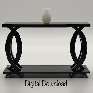 Puede incluir: Una mesa consola negra con un diseño moderno y curvo. La mesa tiene una tapa negra y dos patas curvas a cada lado. Un jarrón blanco se encuentra sobre la tapa de la mesa.