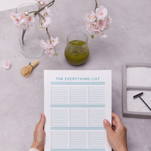 Puede incluir: Una hoja de papel blanca con el texto "THE EVERYTHING LIST" en la parte superior. El papel est&aacute; dividido en tres secciones con l&iacute;neas para escribir. Una persona est&aacute; sosteniendo el papel con sus manos.