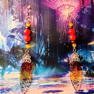 May include: A pair of dangle earrings with red and yellow beads and a feather-like design. The earrings are hanging against a colorful background with a fantasy theme.