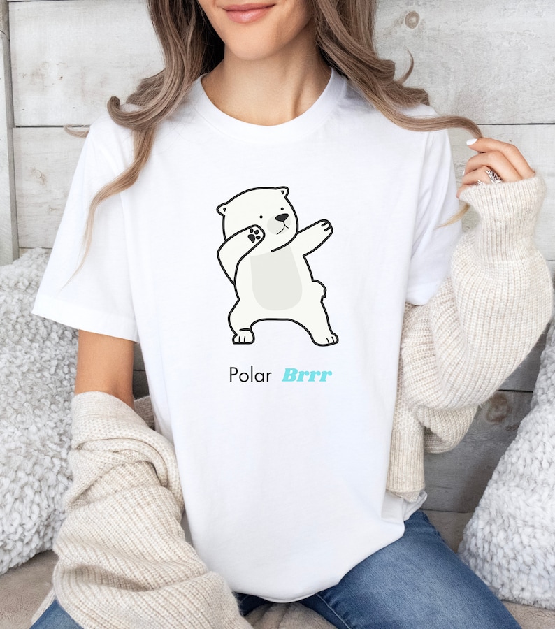 Pode incluir: Camiseta branca com um urso polar de desenho animado fazendo o dab. O texto "Polar Brrr" est&aacute; impresso abaixo do urso.