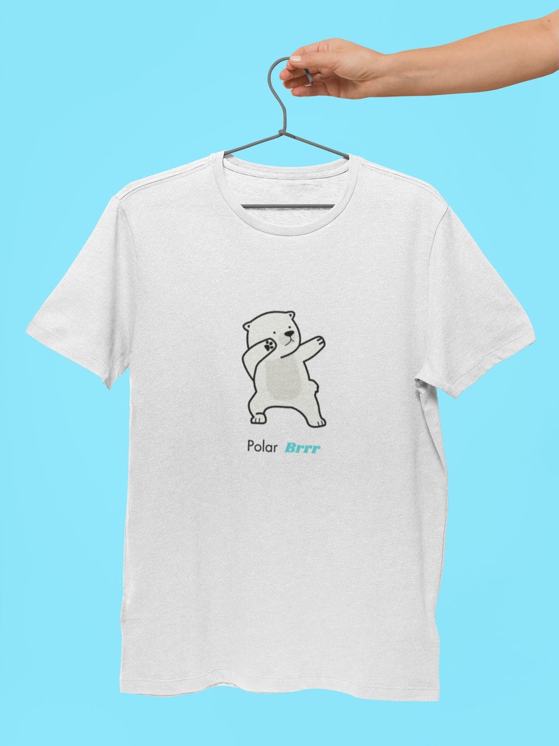 Pode incluir: Camiseta branca com uma ilustra&ccedil;&atilde;o de desenho animado de um urso polar fazendo o dab. O texto "Polar Brrr" est&aacute; impresso abaixo do urso.