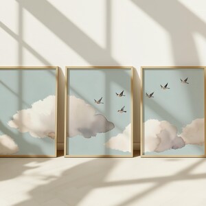 May include: Three framed prints with a minimalist design featuring watercolour clouds and birds flying in a light blue sky.