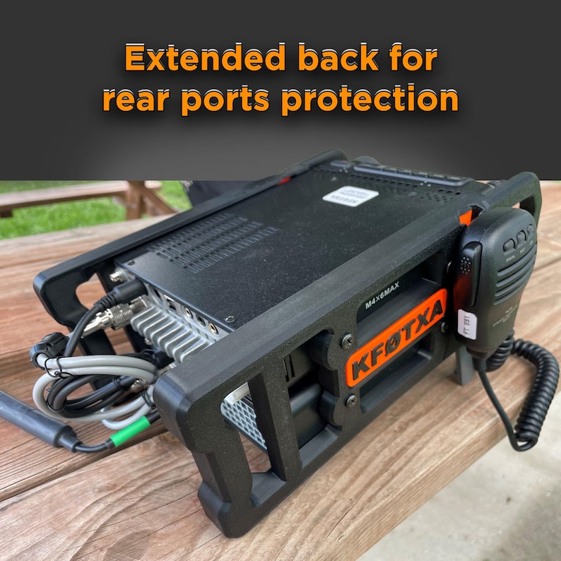 May include: A black radio transceiver housing with an extended back for rear ports protection. The frame features the orange text KF0TXA and M4X6MAX. A black handheld microphone with a coiled cord is attached to the side of the device.