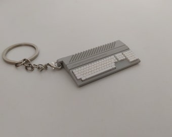 May include: A gray and white computer keyboard keychain with a silver key ring and chain.