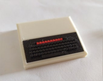 May include: A miniature white computer with a black keyboard and a red power button.