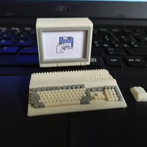 Può includere: Un set di computer in miniatura, con un piccolo monitor bianco sporco che mostra un'immagine pixelata, una tastiera e un pezzo rettangolare separato. La tastiera ha tasti grigi e bianco sporco. Il set è su una superficie scura.