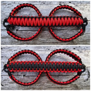 May include: Two red and black paracord loops with a braided strap connecting them. The loops are designed to be used as a handle for a vehicle's roll bar.