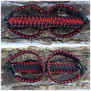 May include: A black and red paracord bracelet with two loops. The bracelet is made with a braided pattern.