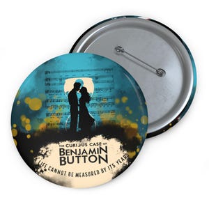 May include: A round button pin featuring a silhouette of a couple in front of sheet music, with a teal and yellow background. The text reads "THE CURIOUS CASE OF BENJAMIN BUTTON A LIFE CANNOT BE MEASURED BY ITS YEARS."