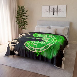 Peut inclure: Couverture en polaire noire et verte avec un motif de cadran d'horloge et le mot "Time" en éclaboussures de peinture blanche.