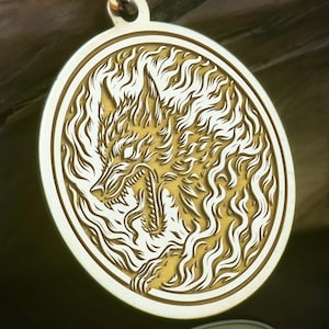 May include: Gold-colored pendant necklace featuring a detailed wolf design within an oval frame. The wolf is depicted with an open mouth and surrounded by a flame-like pattern. The chain and pendant are made of a shiny gold material.