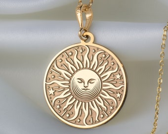 May include: Gold necklace with a round pendant featuring a sun with a face and stars. The pendant is on a white background.