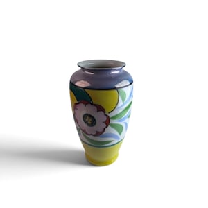May include: A ceramic vase featuring a tapered silhouette with a smooth, flared rim. The surface is decorated with a vibrant, multi-colored floral pattern in shades of yellow, green, blue, and pink, set against a white background.