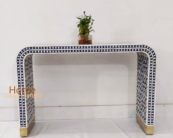 May include: A white console table with a blue and white geometric pattern. The table has a curved design and gold accents on the legs.