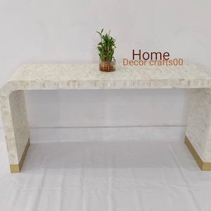 Può includere: Un tavolino da console bianco con un piano curvo e dettagli dorati. Il tavolo è realizzato con piastrelle di madreperla e ha un design moderno. Home Decor crafts00 è stampato sul tavolo.
