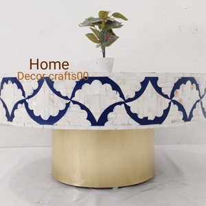 May include: A round white and blue mosaic coffee table with a gold metal base. The table top features a decorative pattern of white and blue floral designs. Home Decor crafts00 is written on the table.