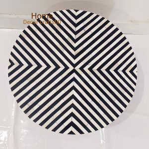 May include: Round black and white bone inlay table top with a geometric pattern. The pattern is made up of black and white stripes that form a diamond shape in the center.