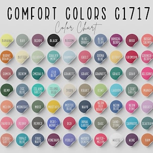 May include: A color chart titled "COMFORT COLORS C1717 Color Chart" displays a variety of colors on circular stickers. Colors include "Banana," "Denim," "Emerald," "Navy," and "Violet." The chart is designed to showcase the available color options.