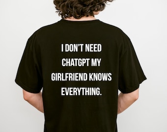 May include: A black short-sleeved t-shirt featuring white text on the back that reads: I DON'T NEED CHATGPT MY GIRLFRIEND KNOWS EVERYTHING. The shirt has a crew neckline and a standard fit, displaying the printed message clearly against the dark fabric.