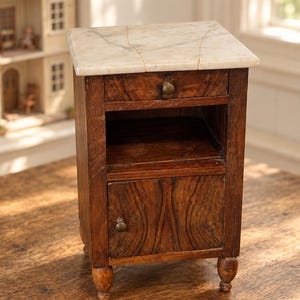May include: A miniature wooden bedside table featuring a white marble top with visible veining, a single small drawer with a round brass knob, an open storage shelf, and a lower cabinet door with a matching brass knob, all supported by four turned legs.