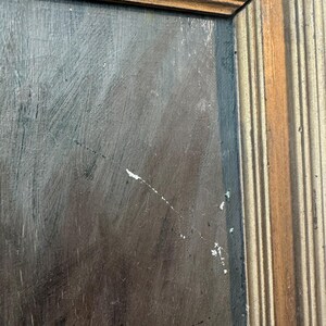 Op de afbeelding: Close-up van een schilderij met een donkere, getextureerde achtergrond. Het schilderij is ingelijst in een goudkleurige houten lijst met een geribbeld ontwerp. Het kunstwerk heeft zichtbare penseelstreken en witte verfspatten.