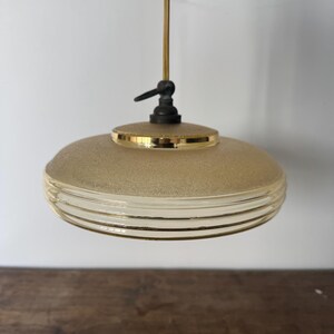May include: A gold and white frosted glass pendant light with a ribbed design. The light has a simple, minimalist style.