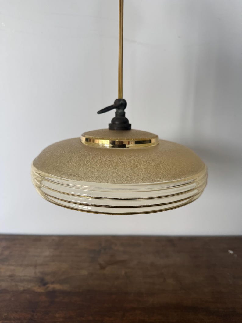 May include: A gold and white frosted glass pendant light with a ribbed design. The light has a simple, minimalist style.