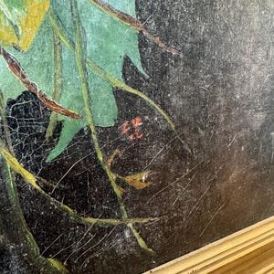 Op de afbeelding: Een antiek schilderij met een gouden lijst. Het kunstwerk toont een donkere achtergrond met groene bladeren en takken. Het schilderij vertoont zichtbare scheuren en slijtage, wat bijdraagt aan de vintage charme. De handtekening van de kunstenaar is zichtbaar in het midden onderaan.