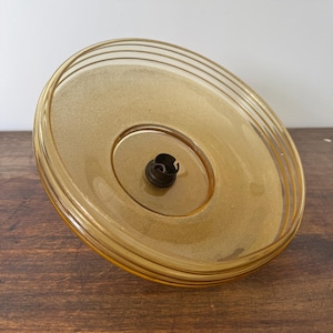 May include: A round, amber-colored glass ceiling light fixture with a single light socket.