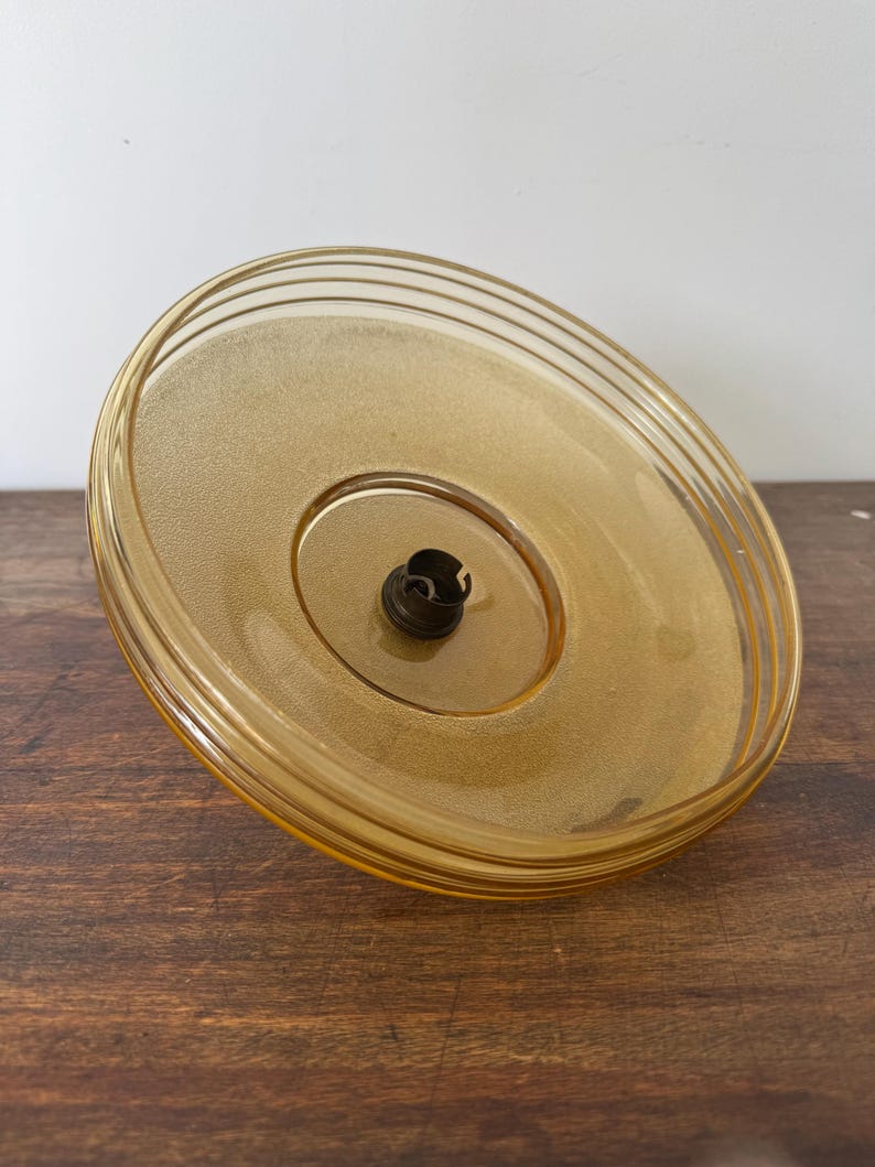 May include: A round, amber-colored glass ceiling light fixture with a single light socket.