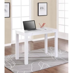 May include: White computer desk with a drawer and a laptop on top. The desk is sitting on a gray rug with a white floral pattern.
