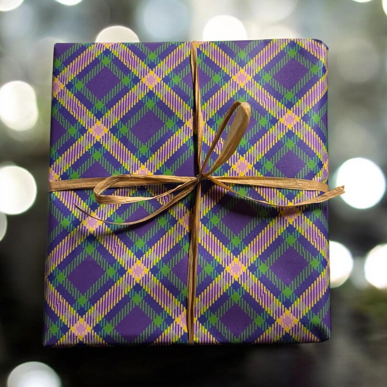 Op de afbeelding: Een cadeaudoos ingepakt in paars, groen, geel en roze geruit cadeaupapier met een bruin lint gebonden in een strik.