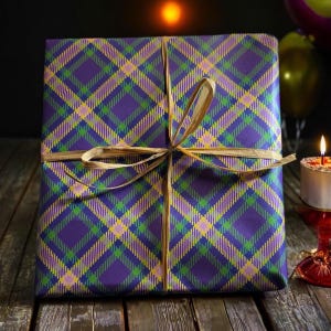 Op de afbeelding: Een paarse en gouden geruite cadeaudoos gebonden met een bruin lint. De doos staat op een houten oppervlak.