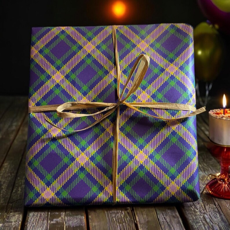 Op de afbeelding: Een paarse en gouden geruite cadeaudoos gebonden met een bruin lint. De doos staat op een houten oppervlak.