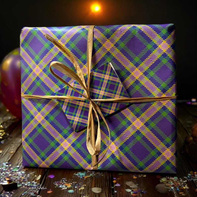 Op de afbeelding: Een paarse, groene en gele geruite cadeaudoos met een gouden lint en strik. De doos is ingepakt in een geruit patroon en vastgebonden met een gouden lint.