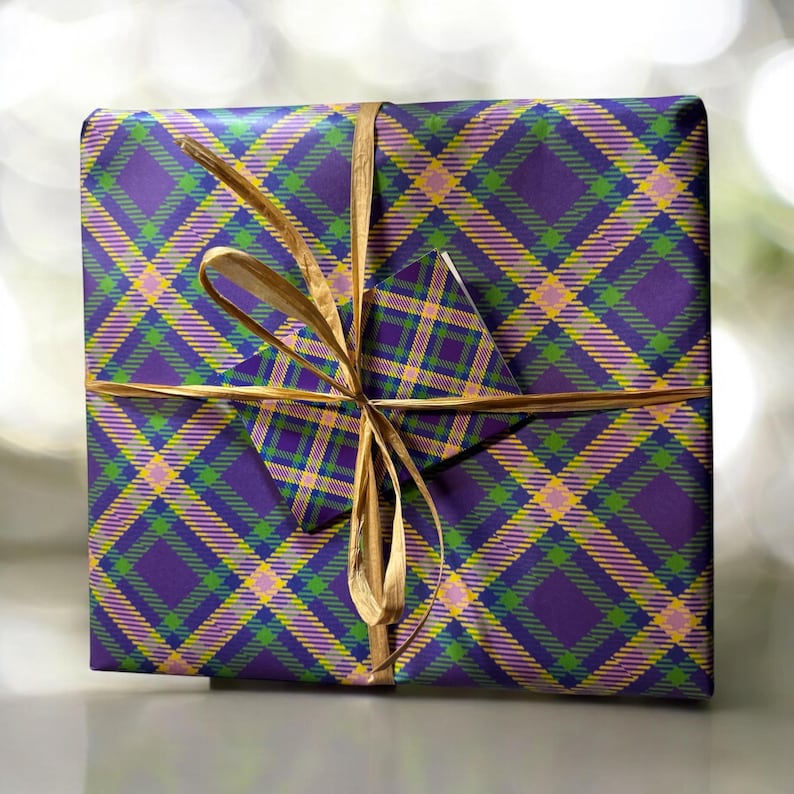 Op de afbeelding: Een paarse, groene en gele geruite cadeaudoos met een gouden lint gebonden in een strik.