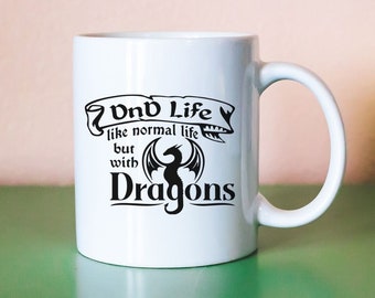 May include: White ceramic mug with a black design that reads "D&D Life like normal life but with Dragons". The design includes a black silhouette of a dragon.