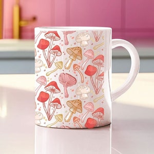 May include: White ceramic mug with a pattern of pink and orange mushrooms. The mug has a white handle.