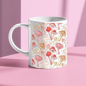 May include: White ceramic mug with a repeating pattern of red, orange, and yellow mushrooms. The mug has a white handle.
