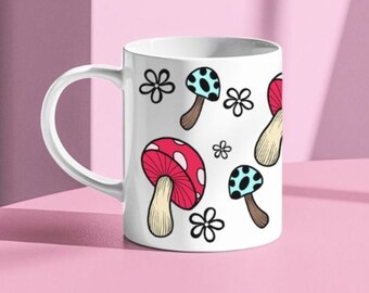 May include: White ceramic mug with a colorful mushroom pattern. The mushrooms are red, blue, and white with black dots. There are also white flowers on the mug.