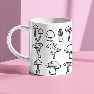 May include: White ceramic mug with a black and white illustration of various mushrooms. The mug has a handle on the left side.