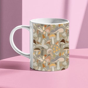 May include: White ceramic mug with a pattern of colorful mushrooms and leaves on a light green background.