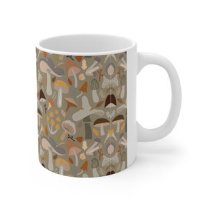 May include: White ceramic mug with a brown and beige pattern of mushrooms and leaves. The mug has a white handle.