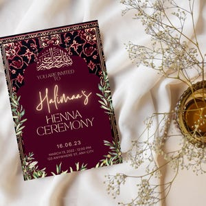 May include: A burgundy invitation card with gold accents and floral designs. The text reads "You are invited to Halima's Henna Ceremony 16.06.23 March 13, 2022 - 12:00 PM 123 Anywhere St, Any City"