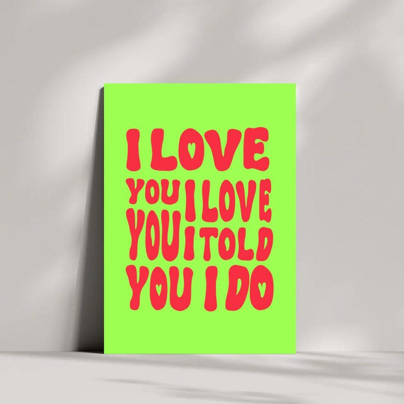 May include: A neon green poster with the words "I LOVE YOU I LOVE YOU I TOLD YOU I DO" in red, bubble-style font. The poster is leaning against a white wall.