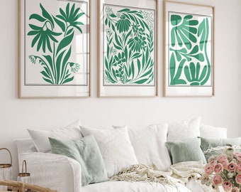 Könnte beinhalten: Drei gerahmte Drucke mit abstrakten grünen Blumenmustern. Die Drucke hängen an einer weißen Wand über einem weißen Sofa mit grünen Kissen.