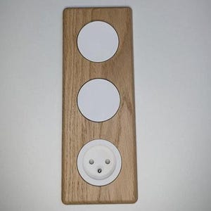 Peut inclure: Une plaque murale en bois avec trois découpes circulaires blanches et une prise électrique blanche.